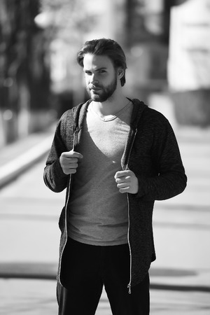 athletic man with beard wearing sportswear fashion, caucasian man, black hoodie and grey shirt, sunny outdoor on blurred background Black and white retro vintage styleの写真素材
