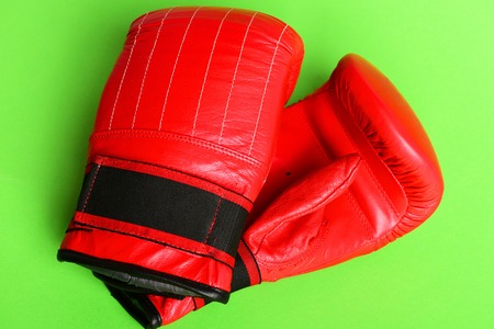 Pair of leather boxing sportswear. Professional box and strong fight concept. Boxing gloves in red color. Sport equipment isolated on bright green backgroundの写真素材