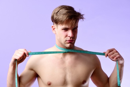 Man with naked torso and measuring tape on purple backgroundの写真素材