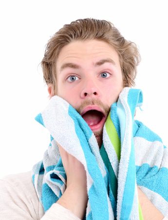 Man with scared face, opened mouth and wet hair wipes his beard. Bathing and morning time concept. Guy with striped blue and white towel isolated on white background. Idea of morning shaving routineの写真素材