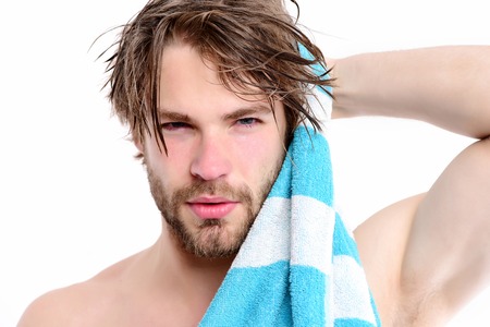 Strength and sportive shape idea. Macho with striped towel and big muscles isolated on white background. Bearded man with naked body and confident face wipes his hair. Shower time and sports conceptの写真素材