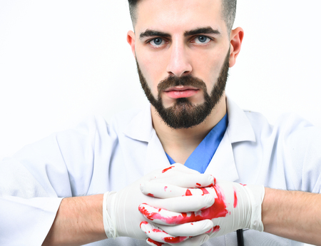 Doctor in latex gloves with confident face expression isolated on white background. Surgeon with hands in blood. Man with beard in medical uniform. Surgery and treatment concept.の写真素材