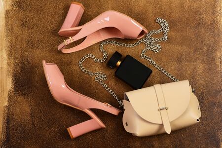 Pair of shoes in pink colour with handbag and perfume bottle. Sandals and purse on brown background. Fashion and beauty concept. Womens shoes and accessories, top view. High heel sandals for summerの写真素材