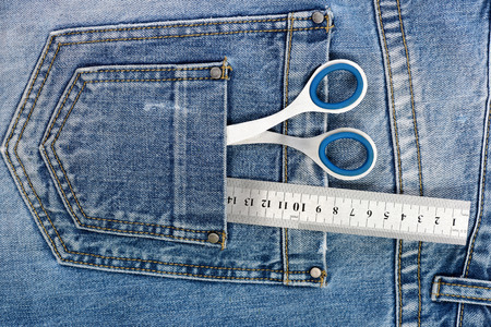 Things for making clothes in back pockets of jeans, top view. Tailoring and design concept. Metal...
