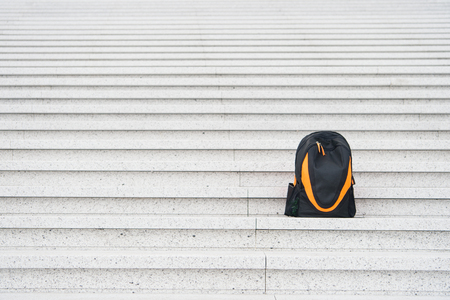 Sport bag on stairs. Traveling and vacation. Black backpack outdoor. Success and loneliness. Beauty and fashion, copy spaceの写真素材