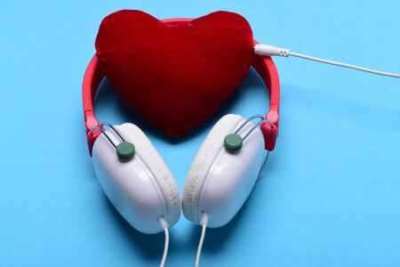 Leisure, music and Valentines day concept. Modern and stylish earphones isolated on turquoise background. Headphones in white and red color with soft heart. Headset for music and heart shaped playerの写真素材