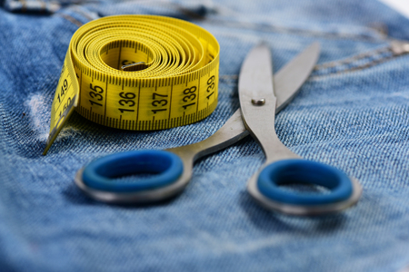 Metal scissors and measure tape on jeans. Making clothes and design concept.  Jeans pocket, close...