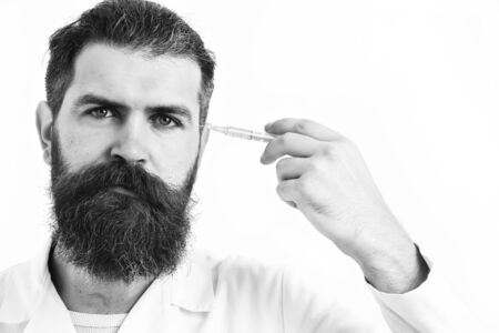 Bearded man, long beard. Brutal caucasian doctor or unshaven hipster, postgraduate student holding syringe in medical gown isolated on white studio background. Medicine conceptの写真素材