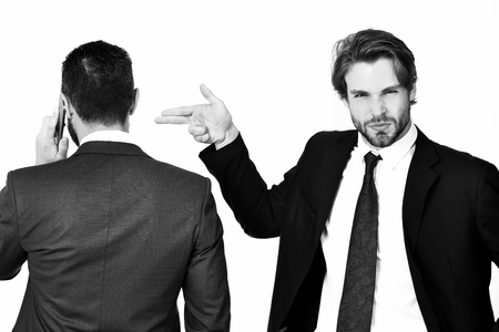 diversion and sabotage, harassment, corruption, man with gun gesture shooting busy businessman speaking on phone in formal suit isolated on white backgroundの写真素材
