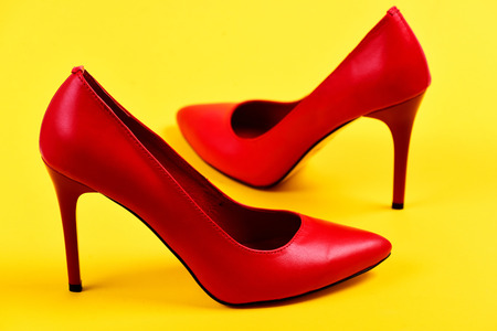 Pair of elegant female shoes, close up. Fashion and beauty concept. Accessories on juicy yellow background. Female shoes in red color. Formal high heel footwear.の写真素材
