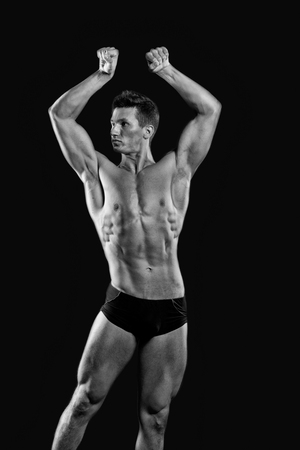 Athletic bodybuilder pose in pants. Adam with bare chest. Sport and workout. Gladiator or atlant. Man with muscular body, black and whiteの写真素材