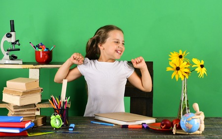 Back to school and childhood concept. Kid and school supplies on green background. Girl with...