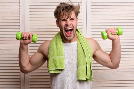 Sportsman screams and doing exercises on beige jalousie background. Fitness and sportive lifestyle...