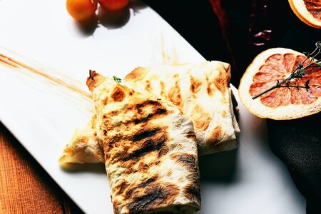 Tasty bread, lavash or pita, roasted rolls, on white plate with dried vegetables natural, red chilly...