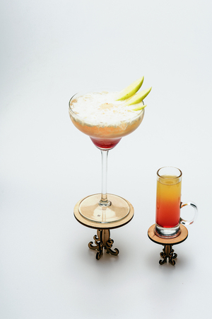 set of alcohol cocktails: sex on the beach and margarita on decorative tables isolated on white background, side viewの写真素材
