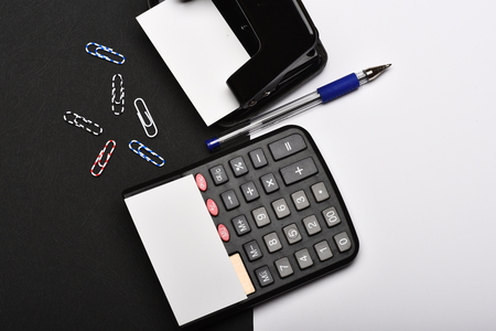 Office tools isolated on black and white background. Hole punch,blank cards, pen and paper clips.  Stationery and calculator, top view. Business and work concept.の写真素材