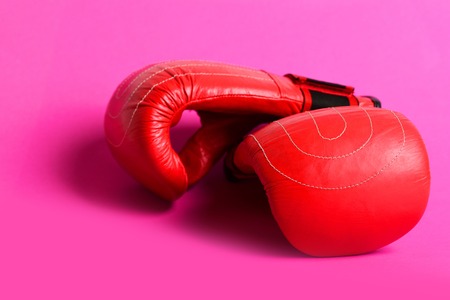 Leather boxing gloves in juicy red color placed on each other isolated on bright pink background....