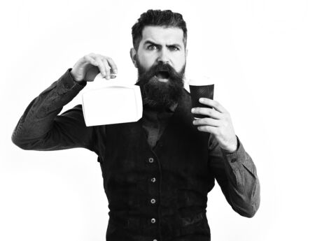 Bearded man, long beard. Brutal caucasian serious hipster with moustache holding coffee cup and meal box in vintage blue shirt and leather vest isolated on white backgroundの写真素材