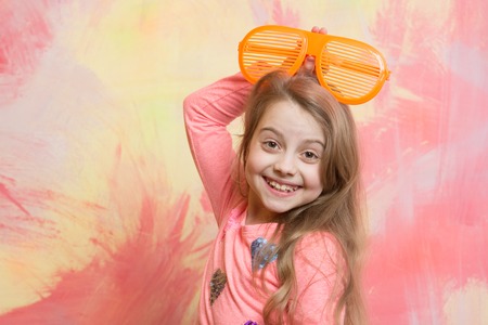 Childhood and happiness. Child girl on colorful background. Small girl in fashionable summer orange glasses. beauty and fashion. glasses on girl kid with happy face.の写真素材