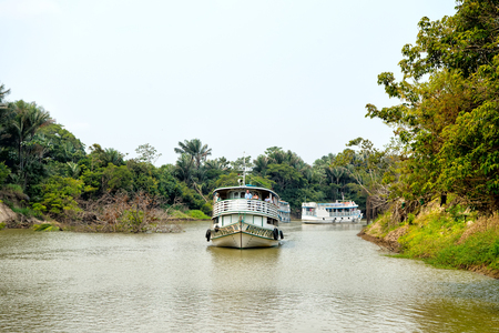 Santarem, Brazil - December 02, 2015: passenger ships floating along river on grey sky on natural background. Water transport and traveling. Summer vacation. Tourist destination concept.のeditorial素材