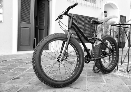 cool sport bicycle with iron and plastic hull and big rubber tyre wheels black color standing on stony road outdoor with nobodyの写真素材