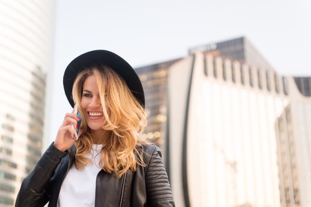 business communication. Girl in fashionable leather jacket with cell phone. communication, business and new technology. woman with happy face in stylish hat speak on phone, copy spaceの写真素材