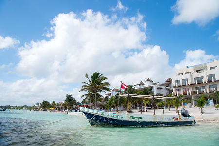 Costa Maya, Mexico - February 01, 2016: boat with flag on tropical beach on clear sea or ocean water, white sand, green palms, tourist resort on sunny day. Summer vacation, travelling conceptのeditorial素材