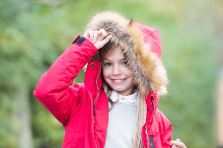 Child in red coat and hood with fur outdoor.の写真素材