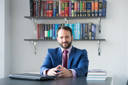 Businessman with laptop sit at desk. Man in blue formal suit at office workplace. Business, entrepreneurship concept. Computer, technology, information. Career, profession, work.の写真素材