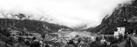 Geiranger, Norway - January 25, 2010: Costa cruiser ship or liner in port, fjord, bay or harbor, calm water with small town on rocky sea shore surrounded by mountains covered with green treesのeditorial素材