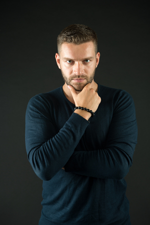 Man touch beard on unshaven face. Macho with stylish hair in blue sweater. Barbershop, male beauty concept. Fashion, style, trend.の写真素材