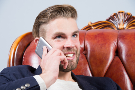 Man or businessman smile and talk on smartphone on sofa. Business communication concept. Entrepreneurship, new technology, modern life.の写真素材