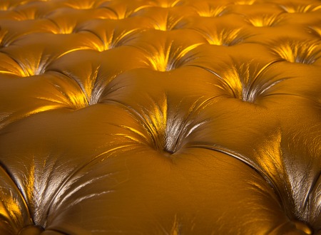 leather background. Upholstery leather pattern padded with buttons on golden background. Furniture, decoration, design concept.の写真素材