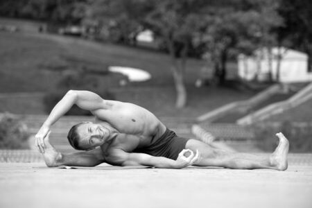 handsome Athletic man doing yoga asanas in the park