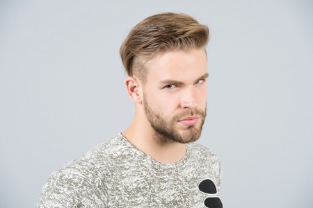 Man in tshirt on grey background. Macho with bearded face and stylish hair, haircut. Fashion, style, trend. Barber salon, barbershop. Grooming, male beauty conceptの写真素材