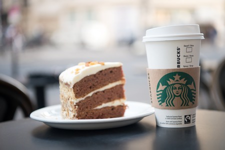Paris , France-September 27, 2017: A tall Starbucks coffee in starbucks coffee shop with cake. Starbucks is the world's largest coffee house with over 20,000 stores in 61 countries.のeditorial素材