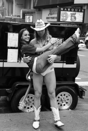New York, USA - November 13, 2008: sexy, naked cowboy model or man in white hat and guitar holding cute girl or pretty woman for photograph on cityscape background. Music and photographingのeditorial素材