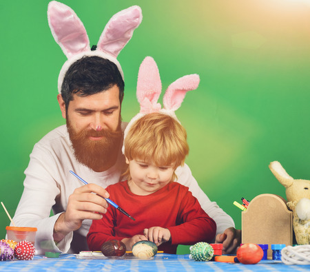 happy easter egg. holiday bunny and eggs, spring flower backround Dad with painted nose wears pink bunny ears. Father and daughter preparing for holiday. Easter celebration and joy concept.の写真素材