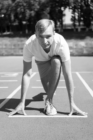 workout and health, sport man start competition running at arena track sunny summer outdoorの写真素材