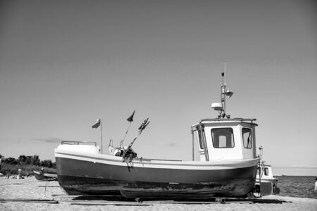 boat or shipfishing marine vessel with colorful flags at moorage on beach on sunny day on blue sea and sky backgroundの写真素材