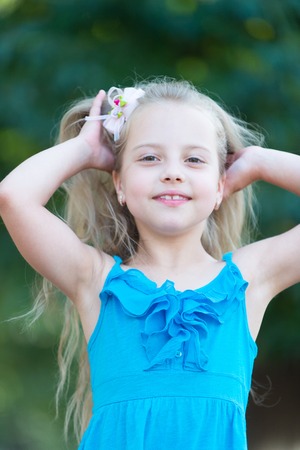Girl smile in park on summer day. Girl smiling with long blond hair.の写真素材