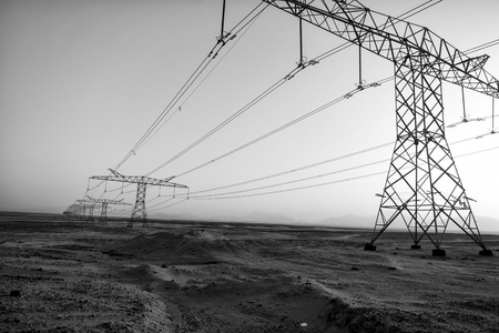 High voltage power lines in desert valley on blue sky background. Electricity distribution stations with wires. Arid landscape. Nature. Energyの写真素材