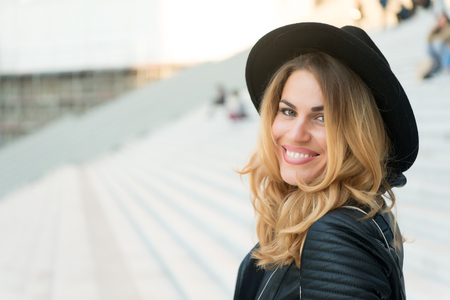 Happy girl smile on stairs outdoor, beauty. Sensual woman in hat with long hair, hairstyle, fashion. Fashion, accessory, style. Beauty, look, makeup. Vacation, travel, wanderlust.の写真素材