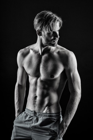 Bodybuilder with sexy torso, six pack, ab, biceps, triceps, muscles. Man athlete show muscular torso in shorts. Sport, bodybuilding, fitness. Healthy lifestyle concept, black and whiteの写真素材
