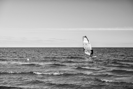Gdansk, Poland - September 19, 2016: windsurfer or man sportsman surfs and sails on board by wind on sea water waves surface inshore on sunny day on blue skyのeditorial素材