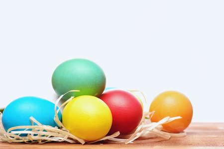 hapyy easter holidays eggs and bunny easter colorful eggs painted in bright colors with straw nest on wood isolated on white background, spring holiday celebration, copy spaceの写真素材