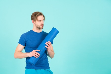 Sportsman with blue yoga mat in hand, gym equipment. Sport, yoga, fitness, pilates. Health, healthcare, bodycare. Workout, training, gym, copy spaceの写真素材