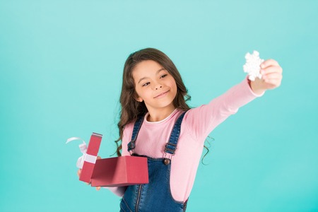 New year, christmas, xmas, eve, holidays celebration. Little girl smile with snowflake from gift box, ribbon bow. Happy child hold present box. Boxing day, punchy pastel trendの写真素材