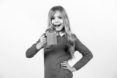 Health and healthy drink. Girl with long blond hair in red sweater hold mug. Tea or coffee break. Thirst, dehydration concept. Child smile with blue cup on orange background.の写真素材