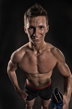 Thirsty athlete smiling with bottle of water. Sportsman smile with sport bottle. Happy man with fit body and torso. Thirst and dehydration concept. Drinking water after training and workout, vintage.の写真素材
